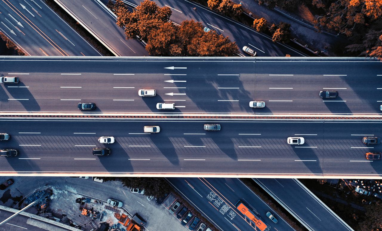 services-01 A high-definition aerial shot capturing multiple lanes of a busy urban highway with cars in motion.